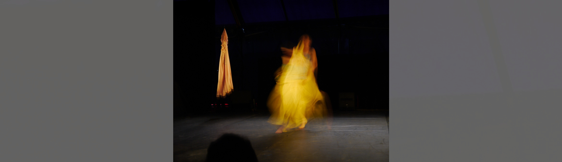 une silhouette jaune toute floue sur une scène où est pendue une robe jaune