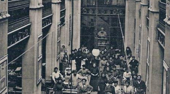 Photo:dans un grand hall ,avec colonnes et arcades, des ouvrières   travaillent sous le regard du buste de Joseph  BARDOU 
